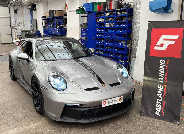 Ein silberner Porsche 911 GT3 steht neben dem Banner der Fastlane Tuning Schweiz GmbH