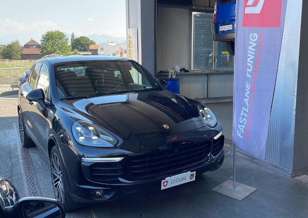 Ein schwarzer Porsche Cayenne Diesel S steht neben der Fastlane Tuning Schweiz Flagge.