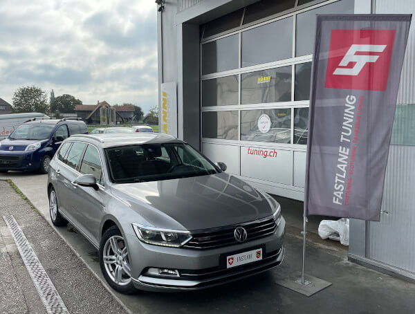 Ein grauer VW Passat Kombi 2.0 TDI SCR steht neben der Fastlane Tuning Schweiz Flagge.